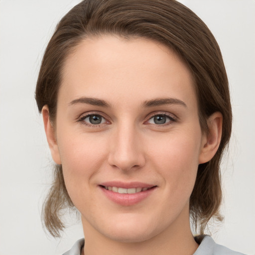 Joyful white young-adult female with medium  brown hair and grey eyes