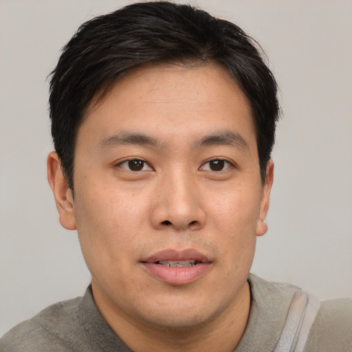 Joyful asian young-adult male with short  brown hair and brown eyes