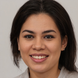 Joyful latino young-adult female with medium  brown hair and brown eyes