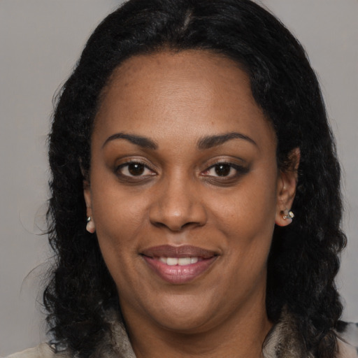 Joyful black adult female with long  black hair and brown eyes