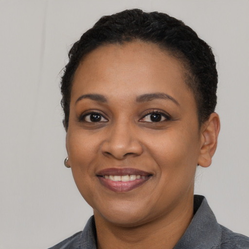 Joyful black young-adult female with short  black hair and brown eyes
