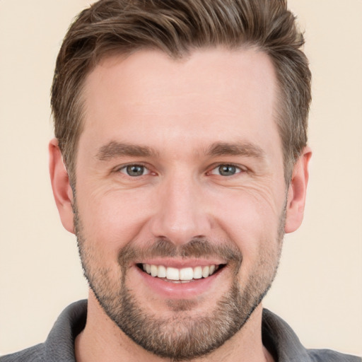 Joyful white young-adult male with short  brown hair and grey eyes