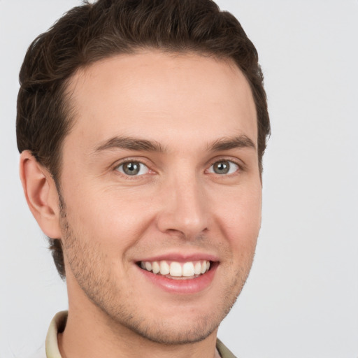 Joyful white young-adult male with short  brown hair and grey eyes