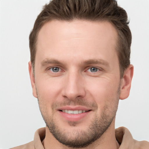 Joyful white young-adult male with short  brown hair and grey eyes