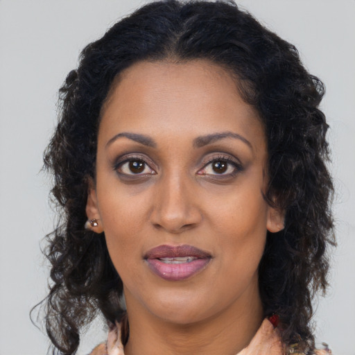 Joyful black adult female with long  brown hair and brown eyes