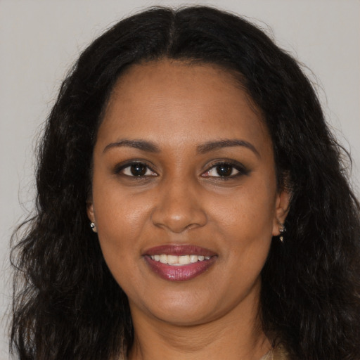 Joyful black young-adult female with long  brown hair and brown eyes