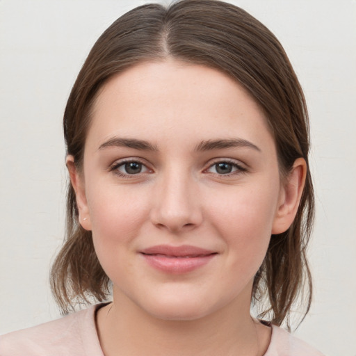 Joyful white young-adult female with medium  brown hair and grey eyes