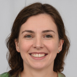 Joyful white young-adult female with medium  brown hair and green eyes