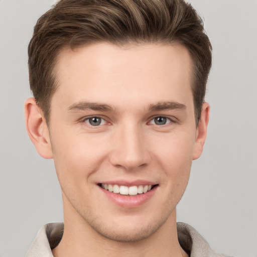 Joyful white young-adult male with short  brown hair and grey eyes