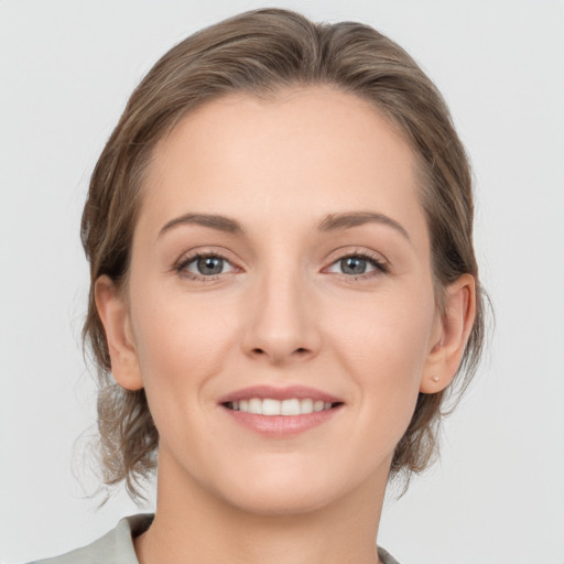 Joyful white young-adult female with medium  brown hair and grey eyes