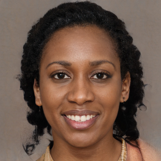 Joyful black young-adult female with long  black hair and brown eyes