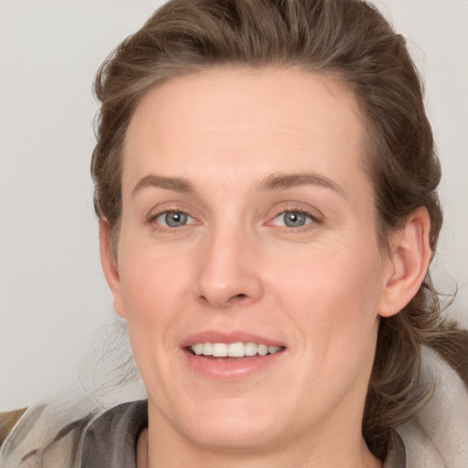 Joyful white young-adult female with medium  brown hair and grey eyes