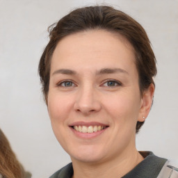 Joyful white young-adult female with short  brown hair and grey eyes