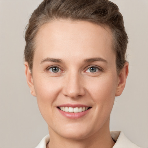 Joyful white young-adult female with short  brown hair and grey eyes