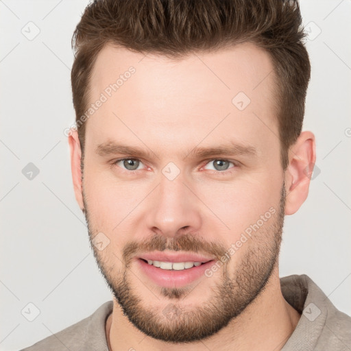 Joyful white young-adult male with short  brown hair and grey eyes