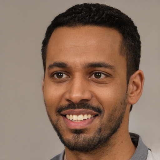 Joyful black young-adult male with short  black hair and brown eyes