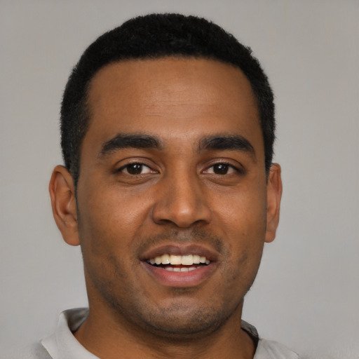 Joyful black young-adult male with short  black hair and brown eyes