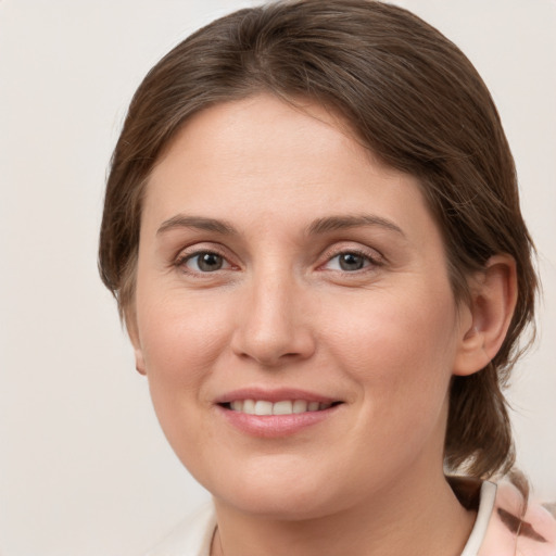 Joyful white young-adult female with medium  brown hair and grey eyes