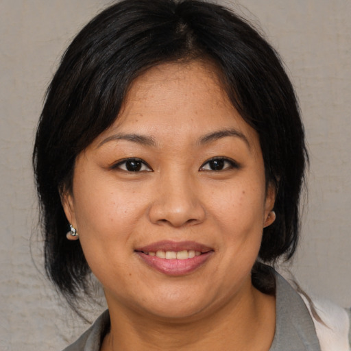 Joyful asian adult female with medium  brown hair and brown eyes