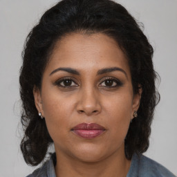 Joyful black adult female with long  brown hair and brown eyes