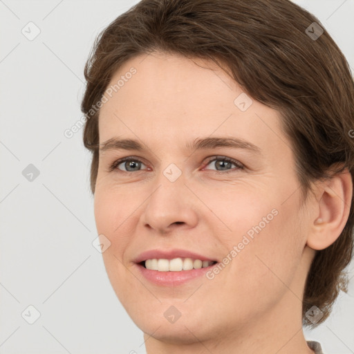 Joyful white young-adult female with medium  brown hair and grey eyes