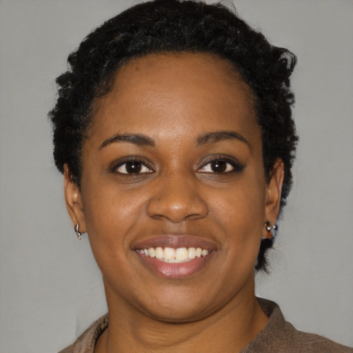 Joyful black young-adult female with short  black hair and brown eyes