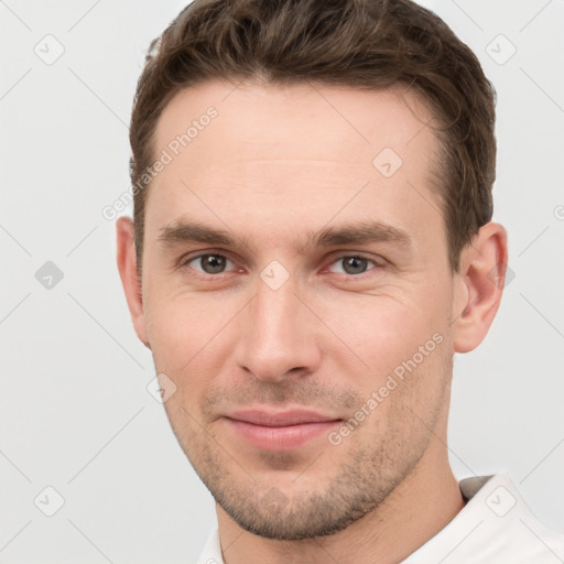 Joyful white young-adult male with short  brown hair and grey eyes