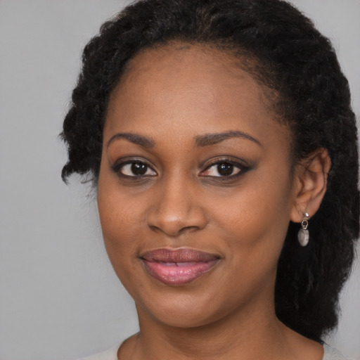 Joyful black young-adult female with long  black hair and brown eyes