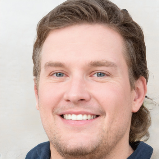 Joyful white young-adult male with short  brown hair and blue eyes