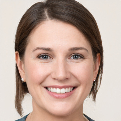 Joyful white young-adult female with medium  brown hair and grey eyes