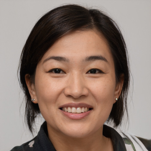 Joyful asian young-adult female with medium  brown hair and brown eyes