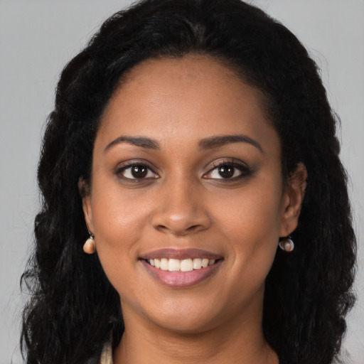 Joyful black young-adult female with long  black hair and brown eyes