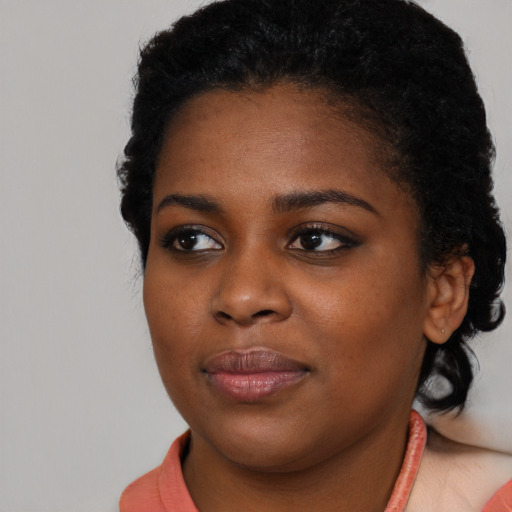 Joyful black young-adult female with short  black hair and brown eyes