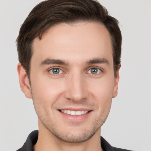 Joyful white young-adult male with short  brown hair and grey eyes