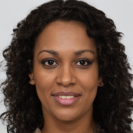 Joyful black young-adult female with long  brown hair and brown eyes