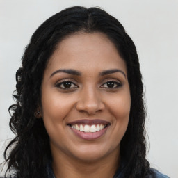 Joyful black young-adult female with long  brown hair and brown eyes