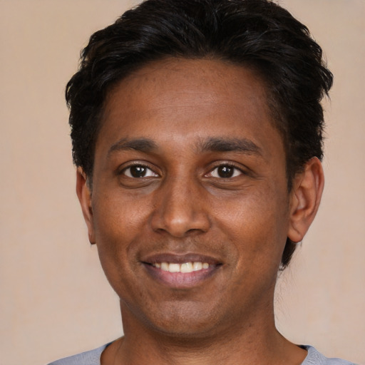 Joyful black young-adult male with short  black hair and brown eyes