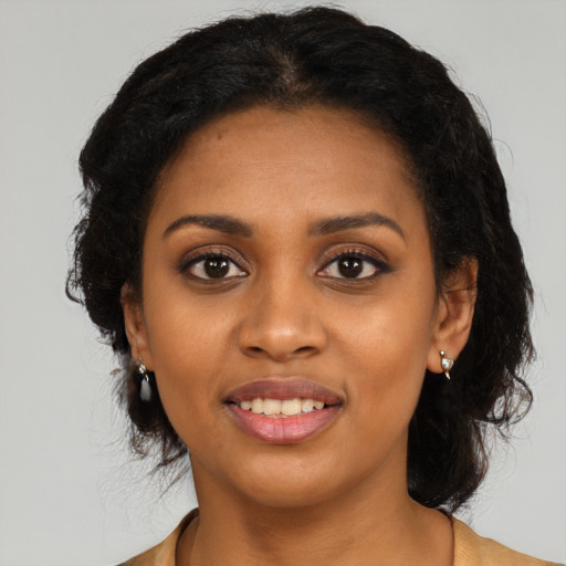 Joyful black young-adult female with long  black hair and brown eyes