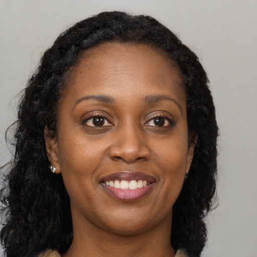 Joyful black young-adult female with long  brown hair and brown eyes