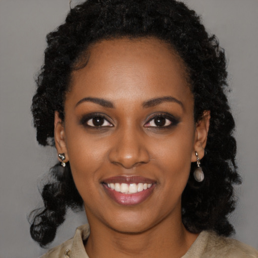 Joyful black young-adult female with long  black hair and brown eyes
