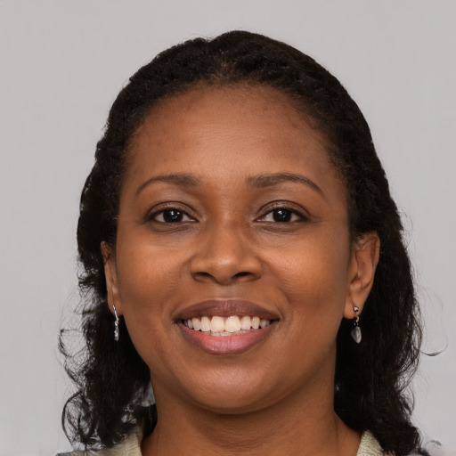 Joyful black young-adult female with long  brown hair and brown eyes