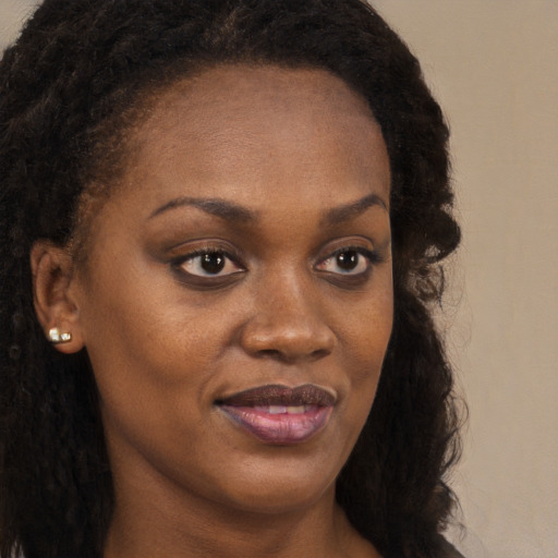 Joyful black young-adult female with long  brown hair and brown eyes