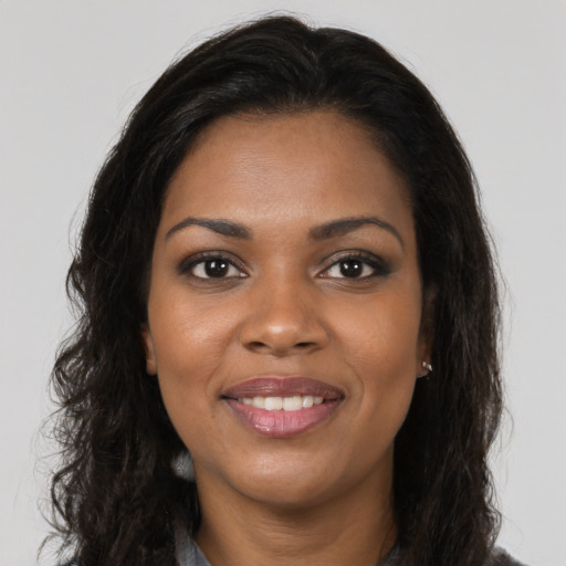 Joyful black young-adult female with long  brown hair and brown eyes