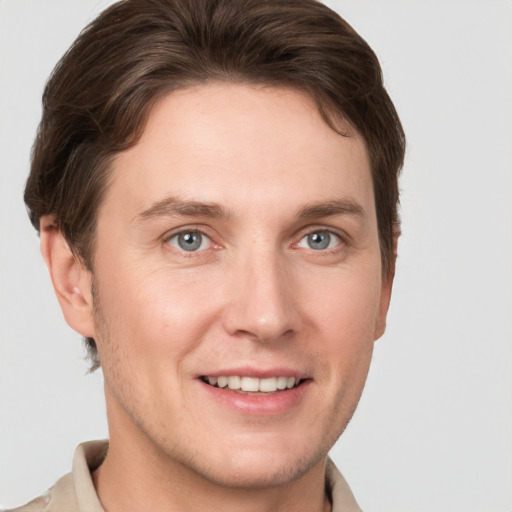 Joyful white young-adult male with short  brown hair and grey eyes