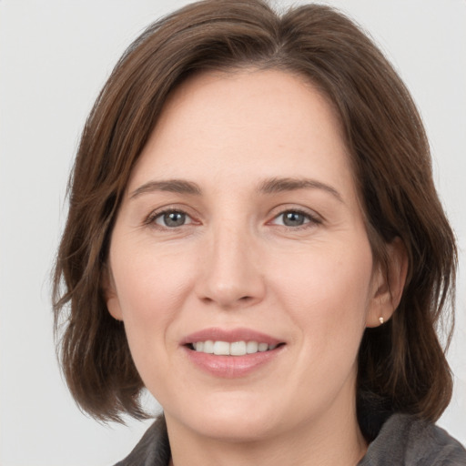 Joyful white young-adult female with medium  brown hair and grey eyes