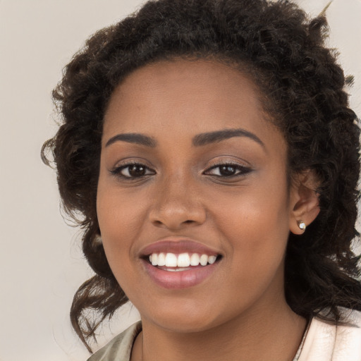 Joyful black young-adult female with long  brown hair and brown eyes