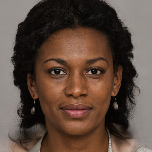 Joyful black young-adult female with long  black hair and brown eyes