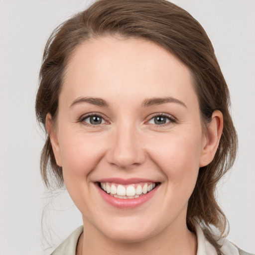 Joyful white young-adult female with medium  brown hair and grey eyes