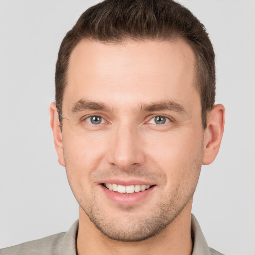 Joyful white young-adult male with short  brown hair and grey eyes