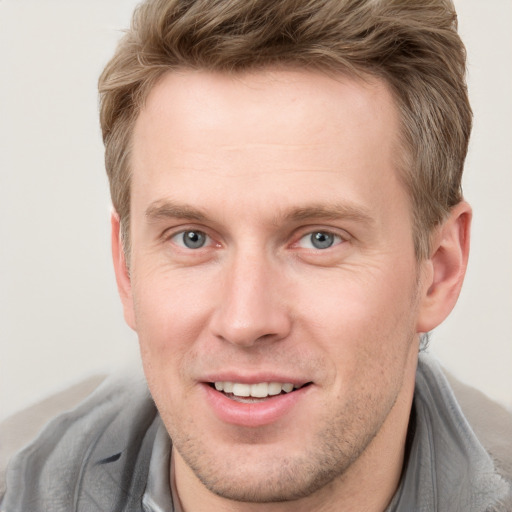 Joyful white young-adult male with short  brown hair and blue eyes